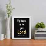 Psalm 39:7 Bible verse wall art with a black background, Lord in yellow. Christian home decor by Infidu. Wall Art displayed on the table in a white frame