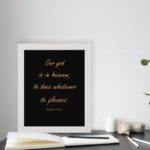 Bible verse wall art with Psalm 115:3 in gold text on a black background. Simple, elegant font centered for easy readability. displayed on the table in a white frame