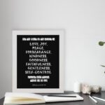 Galatians 5:22-23 Bible Verse Wall Art with White Text on Black Background displayed on the table in a white frame