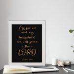 Joshua 24:15 Bible wall art with golden text on a black background, emphasizing LORD in a decorative font. displayed on the table in a white frame