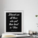 Blessed Are All Those Who Put Their Trust In Him Psalm 2:12 white text on a black background displayed on the table in a white frame - Christian wall art for home decor