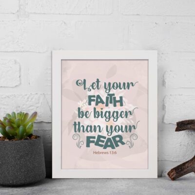 Christian wall art with greenish-blue 'Faith' and 'Fear' text on a light peach floral background. Wall Art displayed on the wall in a white frame