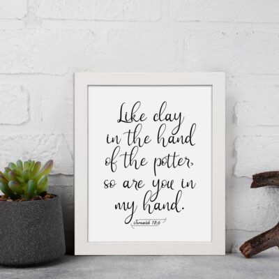 Infidu wall art with the text Like clay in the hand of the potter, so are you in my hand in decorative and standard fonts, black on white background. displayed on the wall in a white frame