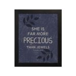 Christian wall art with Proverbs 31:10 verse on purple-blue background with leaf design and black frame hung on the table