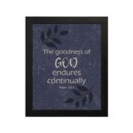 Purple-blue background with black leaf design, white text 'The Goodness Of God Endures Continually Psalm 52:1 Bible Verse Wall Art black frame hung on the wall.