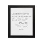 Gray background with leaf design, black and gray text 'And Everyone Who Calls On The Name Of The Lord Will Be Saved Acts 2:21 Bible Verse Wall Art black frame hung on the wall.