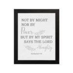 Christian wall art featuring Zechariah 4:6 Bible verse on a gray background with gray leaf design and black and gray font and black frame hung on the wall.