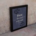 Christian wall art with purple-blue background, black leaf design, and white text Bless The Lord O My Soul Psalm 103:1 Bible Verse Wall Art black frame on the wall