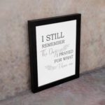 Christian wall art featuring the phrase I Still Remember The Days I Prayed For What I Have Now on a gray background with a gray leaf design and black and gray font black frame on the wall.