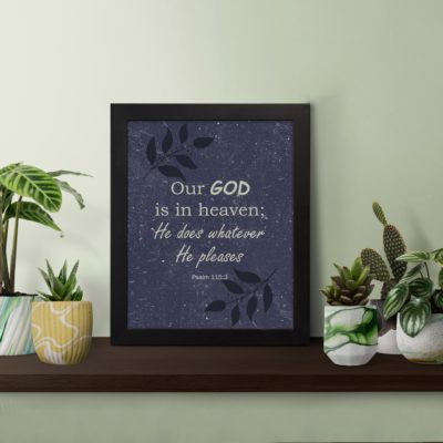 Christian wall art with Psalm 115:3 text on a Purple Blue Color background, black leaf design, white font black frame displayed on the table