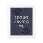 Purple-blue background with black leaf design, white text Jesus Loves Me Bible Verse Wall Art white frame hung on the wall.