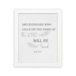 Gray background with leaf design, black and gray text 'And Everyone Who Calls On The Name Of The Lord Will Be Saved Acts 2:21 Bible Verse Wall Art white frame hung on the wall.