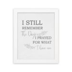 Christian wall art featuring the phrase I Still Remember The Days I Prayed For What I Have Now on a gray background with a gray leaf design and black and gray font white frame hung on the wall.