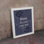 Christian wall art with purple-blue background, black leaf design, and white text Bless The Lord O My Soul Psalm 103:1 Bible Verse Wall Art white frame on the wall