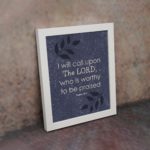 Christian wall art with purple-blue background, black leaf design, and white font featuring Psalm 18:3 white frame on the wall