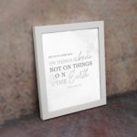 Gray background with leaf design, black and gray text 'Set Your Affection On Things Above Colossians 3:2 Bible Verse Wall Art and white frame on the wall.