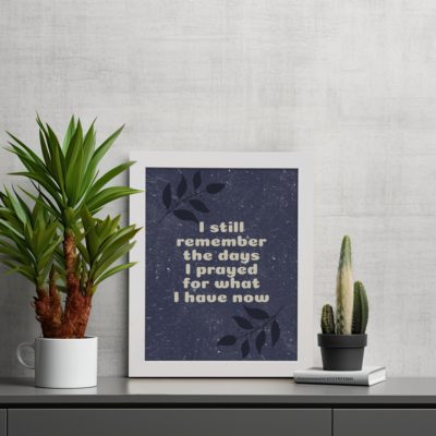 Infidu, I still remember the days I prayed for what I have now. Bible Verse wall art with a purple-blue background, black leaf design, and white font is perfect for home office decor and white frames on the table.