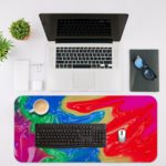 Infidu Artistic Desk Pad with swirling, marbled pattern in vibrant colors of red, blue, purple, green, and yellow. Desk Mat with an Apple Laptop