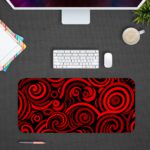 Desk pad with bold red and black spirals on a dark background, creating a hypnotic effect. Desk Pad kept on a gray background