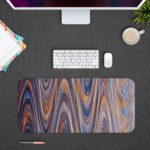 Infidu Artistic Patterns Desk Mat with smooth, flowing marble-like design in soft blue, white, and gray with light brown accents.Desk Pad with Design Kept on a computer table