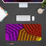 Infidu Artistic Patterns Desk Pad with a geometric zigzag pattern in warm hues of red, purple, and yellow, featuring a textured look. Desk Pad with Design Kept on a computer table