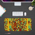 Infidu Artistic Patterns Desk Mat featuring a detailed geometric grid in earthy tones like green, yellow, red, and brown. Desk Pad with Design Kept on a computer table