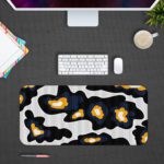 Infidu Artistic Patterns Desk Pad with a black background and large, irregular white and orange abstract shapes. Desk Pad with Design Kept on a computer table