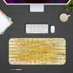 Infidu Artistic Patterns Desk Pad with a yellow and light brown background and vibrant abstract patterns in orange, green, and white. Desk Pad with Design Kept on a computer table