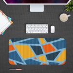 Infidu Artistic Pattern Desk Pad - Blue background with abstract shapes in orange, yellow, and light blue Design Kept on a computer table