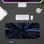 Infidu Minimalist Design Desk Pad features a blue and black background with abstract vector art, resembling speed lines or a starburst effect. Design Kept on a computer table