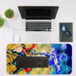 Infidu Artistic Desk Mat with dynamic swirling abstract pattern in yellow, red, and blue on a dark background. Desk Mat with an Apple Laptop