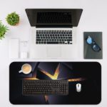 Desk pad with a dark background and sharp golden shapes resembling shattered glass, with a bright center point. Desk Mat with a laptop