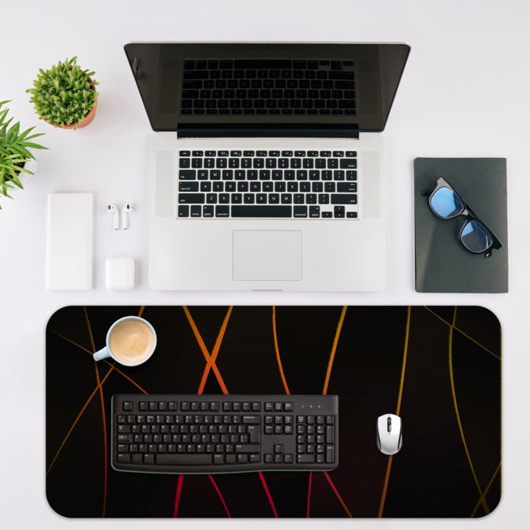 Golden curved lines crisscrossing on a black background, create a dynamic and elegant abstract design. Desk Mat with an Apple Laptop