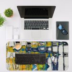 Infidu Artistic Desk Mat with abstract cityscape design in yellow and blue with white lines. Desk Mat with an Apple Laptop