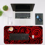 Desk pad with bold red and black spirals on a dark background, creating a hypnotic effect. Desk Mat with a laptop