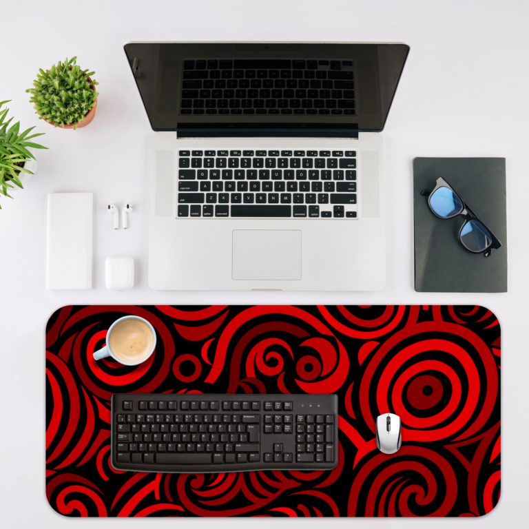 Desk pad with bold red and black spirals on a dark background, creating a hypnotic effect. Desk Mat with a laptop