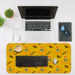 Desk pad with a bright yellow background featuring black curved lines and blue circular shapes. Desk Mat with a laptop