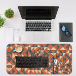 Desk pad with an abstract geometric pattern in blue, orange, and white, featuring triangles and various shapes. Desk Mat with an Apple Laptop