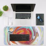 Abstract swirl pattern with vibrant red, yellow, purple, and blue colors on a light blue and white background. Desk Mat with an Apple Laptop