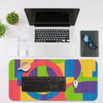 Infidu Artistic Patterns Desk Pad with colorful geometric shapes in pink, green, yellow, blue, and purple. Desk Mat with an Apple Laptop