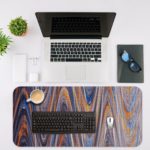 Infidu Artistic Patterns Desk Mat with smooth, flowing marble-like design in soft blue, white, and gray with light brown accents. Desk Mat with an Apple Laptop