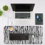 Infidu Artistic Patterns Desk Pad with vertical black and white lines creating a dense, forest-like pattern and optical illusion effect. Desk Mat with an Apple Laptop