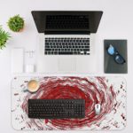 Infidu Artistic Desk Pad with a swirling vortex pattern in red, white, and black. Desk Mat with an Apple Laptop