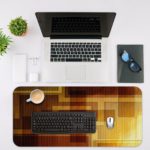 Infidu Artistic Patterns Desk Mat featuring a layered design of overlapping squares and rectangles in warm neutral tones like brown and beige. Desk Mat with an Apple Laptop