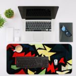 Infidu Artistic Patterns Desk Pad with sharp, jagged shapes in a zigzag design featuring bold colors like red, white, green, and black. Desk Mat with an Apple Laptop