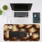 Infidu Artistic Patterns Desk Pad with a dark brown and black wave-like pattern highlighted with golden accents, creating a warm glow. Desk Mat with an Apple Laptop