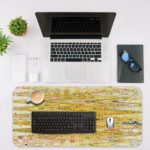 Infidu Artistic Patterns Desk Pad with a yellow and light brown background and vibrant abstract patterns in orange, green, and white. Desk Mat with an Apple Laptop