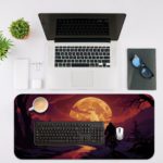 Infidu Desk Pad with a silhouette of a person on horseback by water, set against a sunset sky in deep purples, pinks, and oranges. Desk Mat with a computer