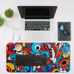 Desk pad with a vibrant, abstract cartoon doodle design featuring bold colors and playful shapes. Desk Mat with an Apple Laptop