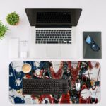 Infidu Artistic Desk Pad with abstract brushstroke pattern in red, blue, and black on a white background. Desk Mat with an Apple Laptop